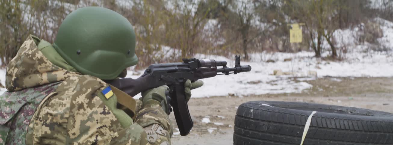 A Ukrainian soldier fires an assault rifle in slow motion at an outdoor shooting range during winter
