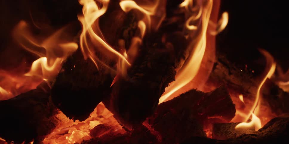 Intense close-up of burning wood logs with dancing flames and glowing embers