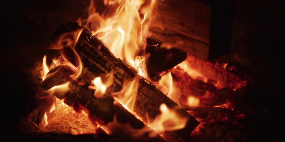 A warm and cozy campfire burns brightly in slow motion, with glowing embers and dancing flames