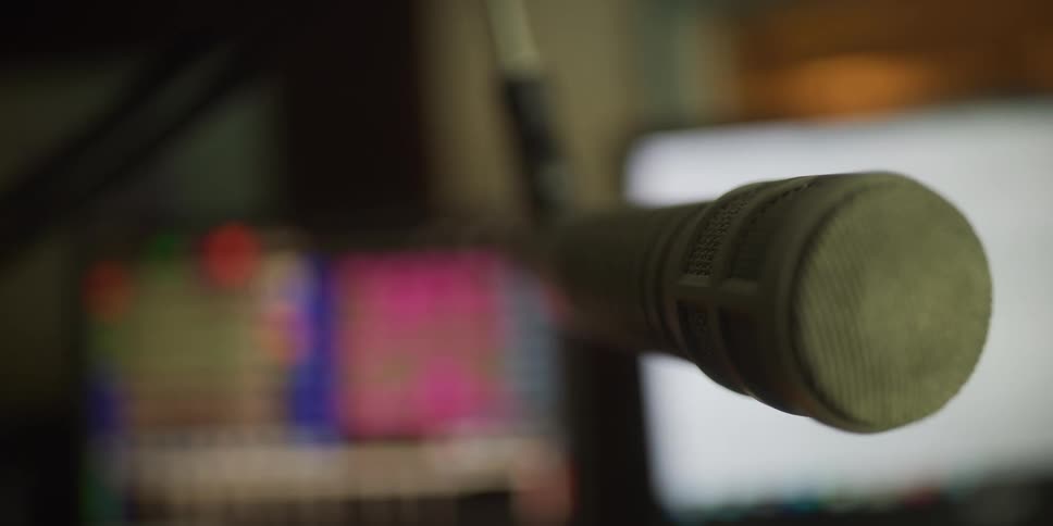 A slow rack focus reveals the details of a professional microphone in a recording studio