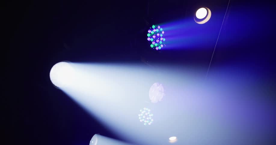 Looking up at a professional stage lighting rig with spotlights and colored LEDs illuminating the dark