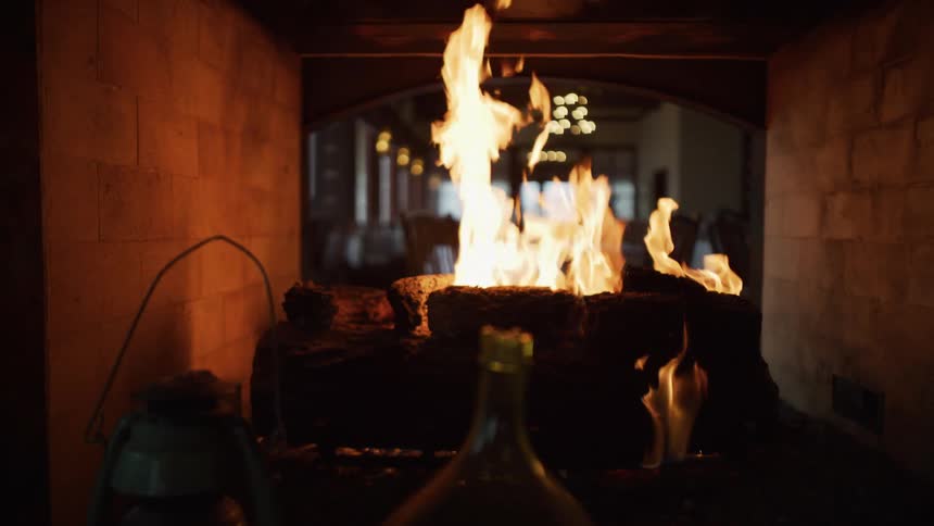A warm and cozy fire burns in slow motion inside a rustic brick fireplace, creating a relaxing ambiance