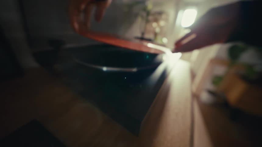 Close up of hands placing a red vinyl record onto a turntable and closing the dust cover