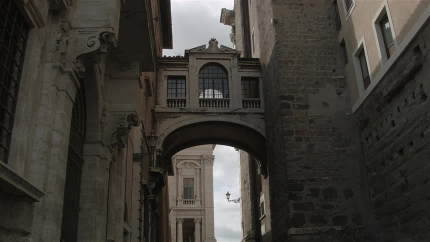 The alley has a arch with a walkway between buildings