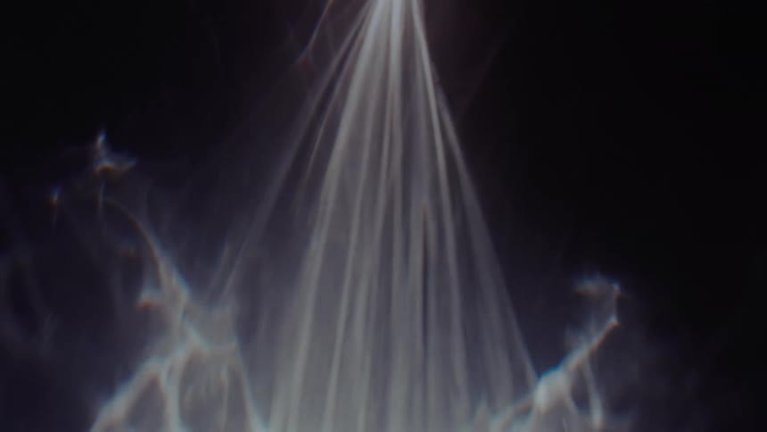 A single beam of ethereal white light slowly expands and radiates against a dark black background