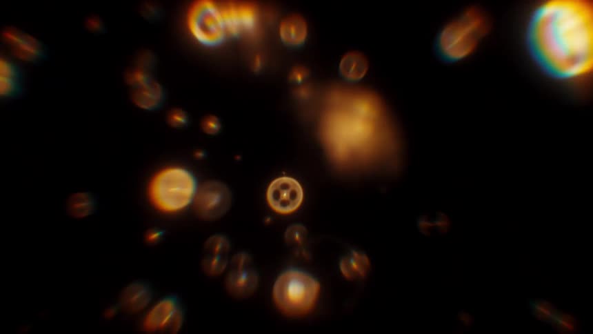 Abstract golden bokeh particles with prismatic light refraction float and drift through a dark space