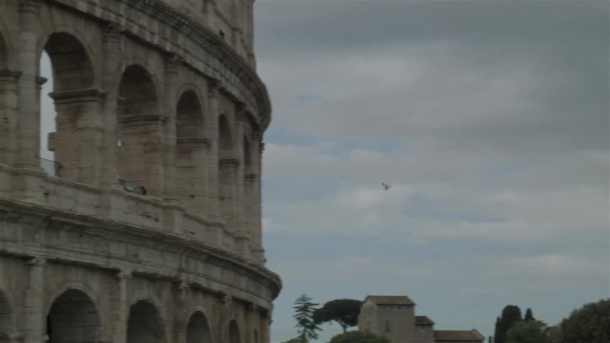 A bird flies in the sky landing on the coliseum in rome
