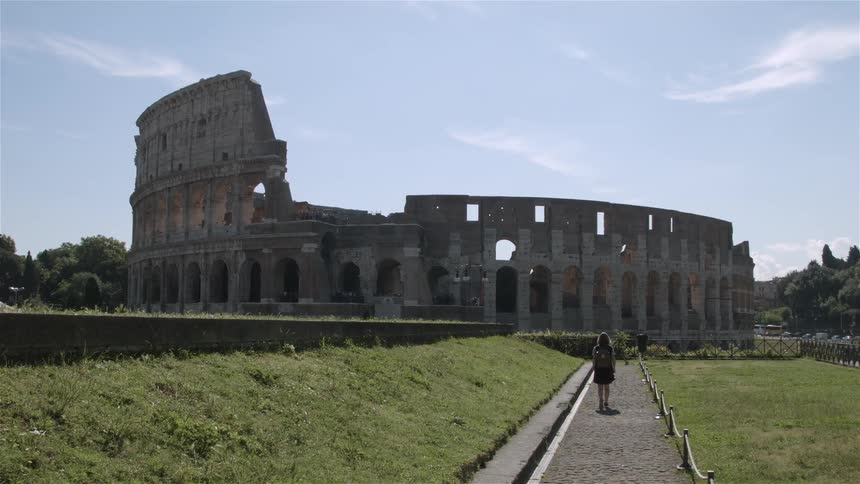 Woman walking down a long path to an old building