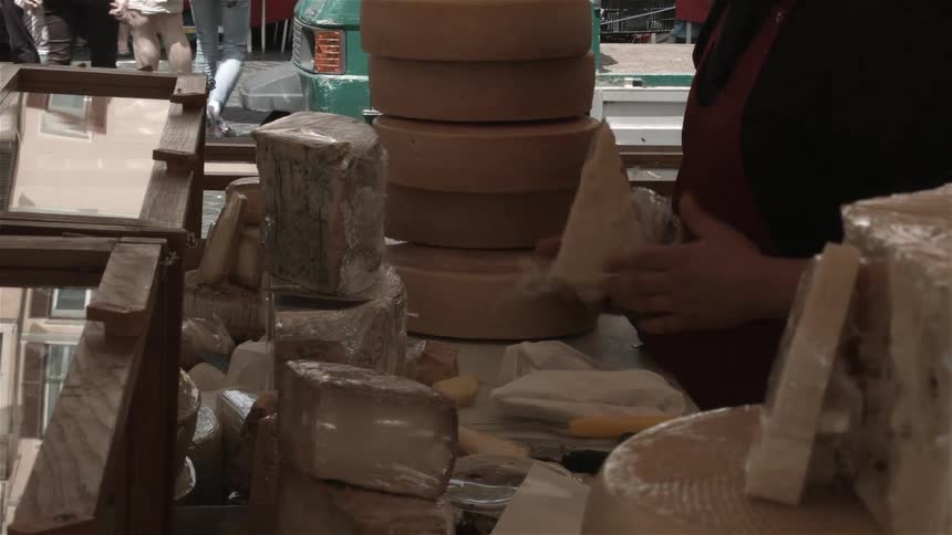A person is working at a food stand wrapping cheese