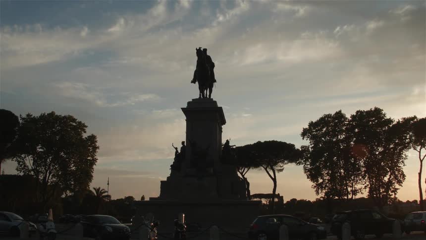 A statue stands tall above parked cars