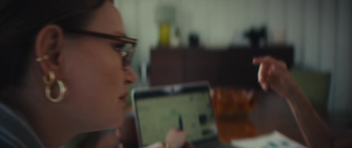 A close-up rack focus shot of an older woman instructing a younger woman as they collaborate over a laptop at a table