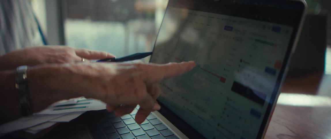 Two businesswomen collaborate and analyze financial performance charts on a laptop screen during a meeting