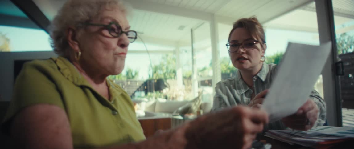 A financial advisor explains paperwork to a surprised senior woman in her bright and modern home