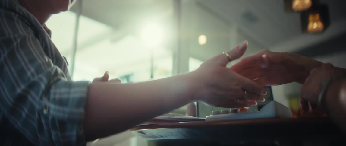 A professional woman offers a reassuring handshake and holds an elderly client's hand in a sunlit office