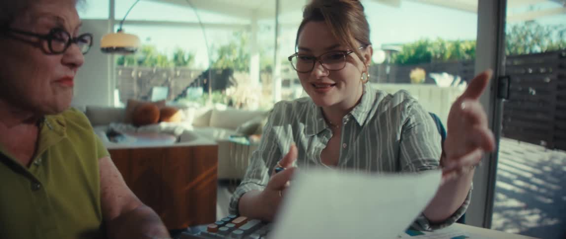 A financial advisor patiently explains a report to a senior client during a home visit