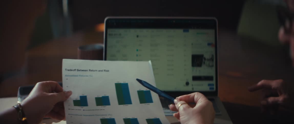 A financial advisor reviews investment charts and data on a laptop with a senior client during a consultation