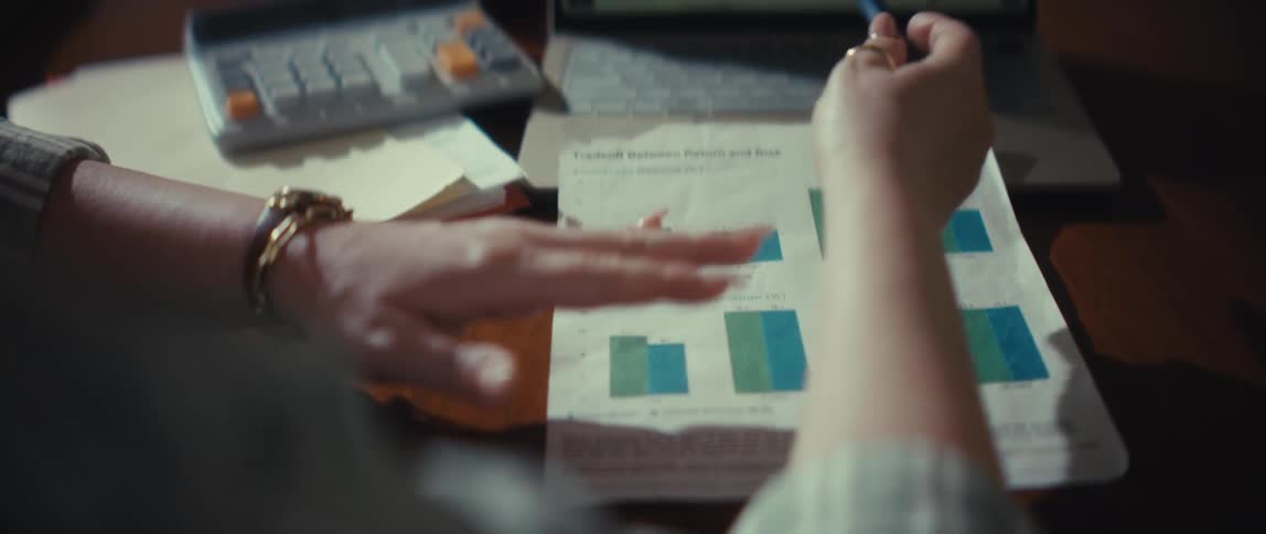 A financial consultant smiles as she explains investment charts and cryptocurrency market data on a laptop to a client