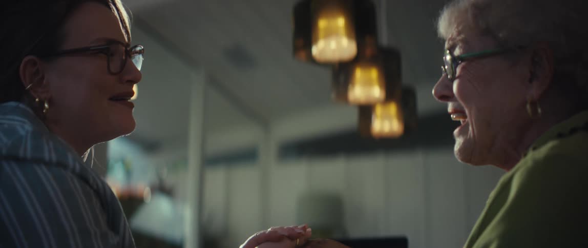 A young woman gently holds the hands of an elderly woman in a tender moment of connection and support