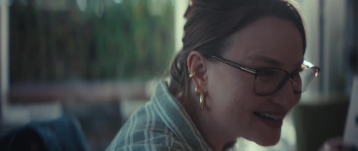 A smiling businesswoman with glasses excitedly presents a bar chart during a collaborative meeting