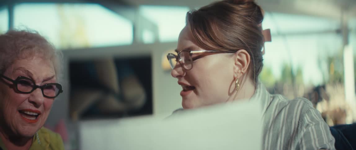 An excited young woman shows positive financial results on a chart to a happy senior woman in slow motion