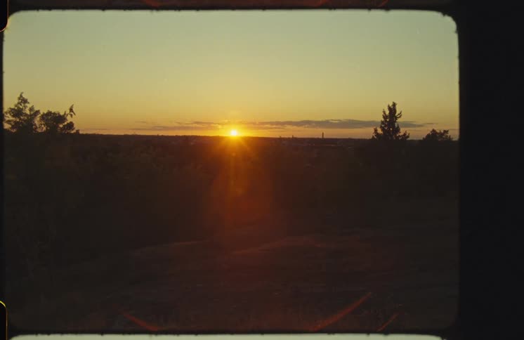 A peaceful sunset shines over a silhouetted landscape in this authentic Super 8mm film shot