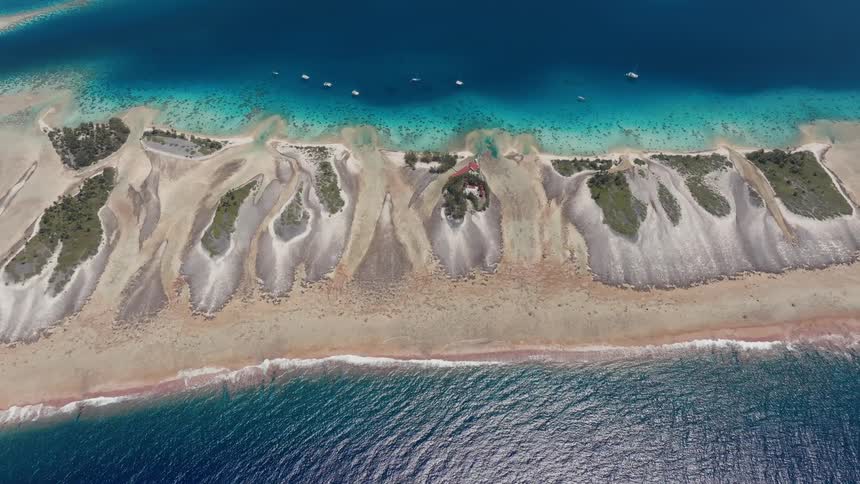 A spectacular high-angle aerial view showcases the stunning natural beauty of the Fakarava atoll in French Polynesia, with its unique coral formations and contrasting blue waters