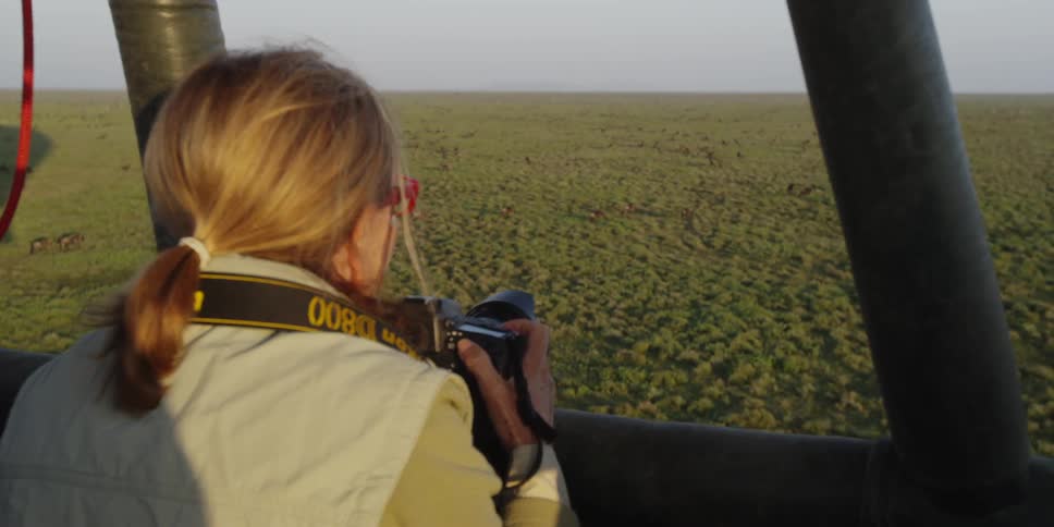 Woman riding in a hot air balloon holding a camera
