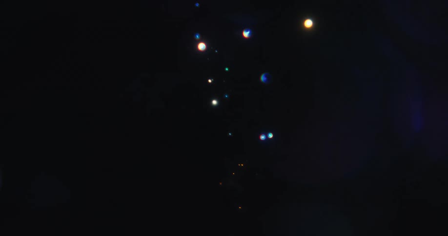 Magical multicolored bokeh lights and shimmering particles float and fade in a dazzling abstract display