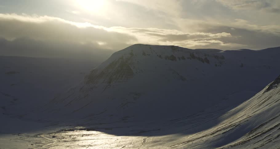 A serene and dramatic time-lapse captures the shifting sunlight across a vast, frozen mountain landscape