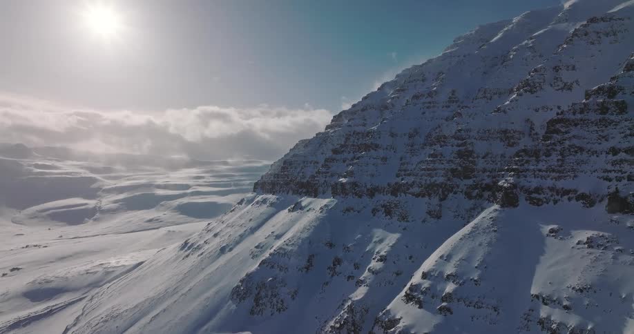 A cinemagraph shows the bright sun shining on a vast, snow-covered mountain during winter
