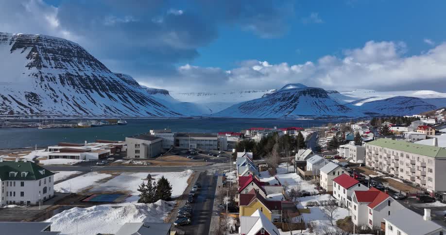 Ascending aerial view of the picturesque coastal town of Ísafjörður, Iceland, nestled in a snowy fjord