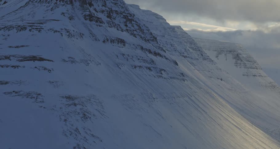 Majestic aerial ascent over a vast, snow-covered mountain range in Iceland at dusk