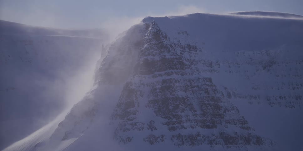 Close up of a snow-covered mountain peak with strong winds causing a blizzard