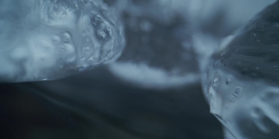 A close-up, abstract view of glacial ice formations with cold water flowing beneath