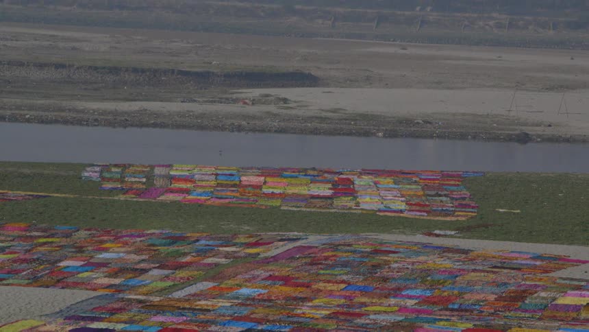 Aerial view of brightly colored patches of laundry, a body of water and mountains