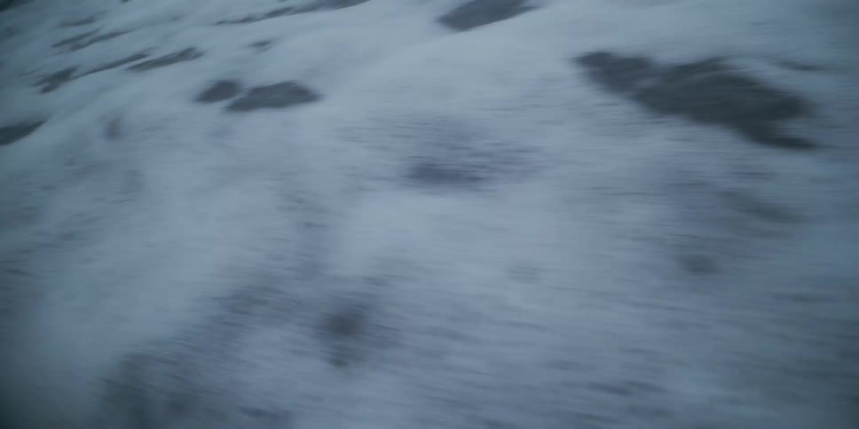 Close up of foamy ocean waves gently washing over the dark sand of a beach at dusk