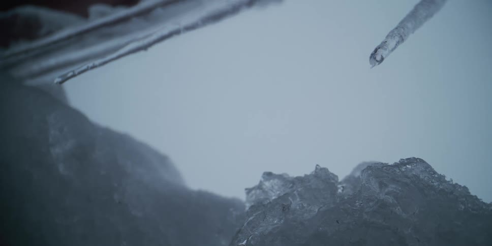 Super slow motion macro shot of a water drop falling from a melting icicle during winter
