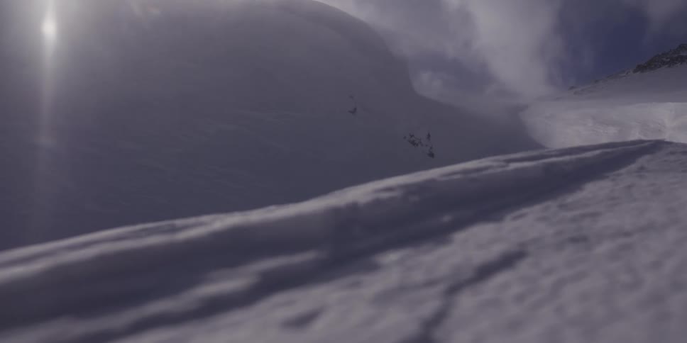 A slow-motion pan over a windy, snow-covered mountain reveals a vast and desolate landscape