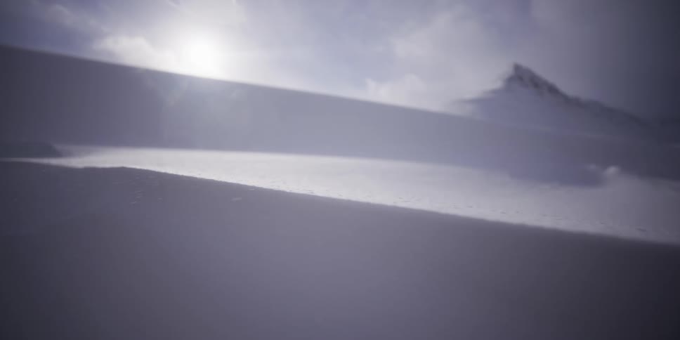 A slow-motion close-up of fierce winds blowing snow across a vast, sunlit mountain landscape
