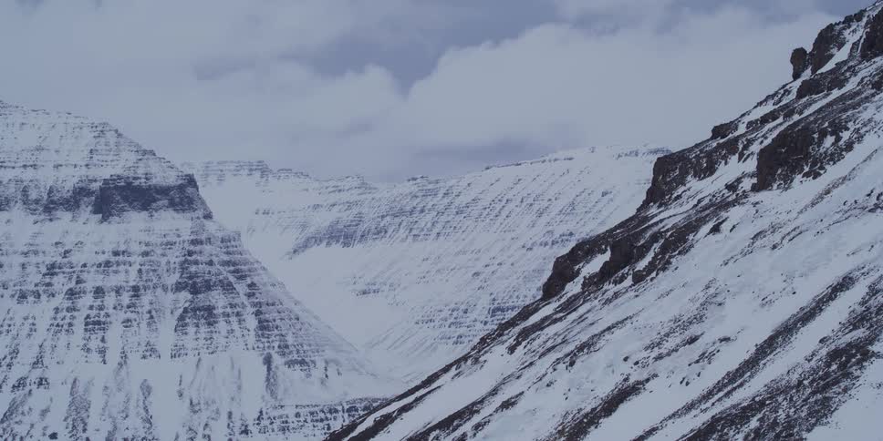 Epic time-lapse of clouds rolling over a vast and majestic snow-covered mountain valley