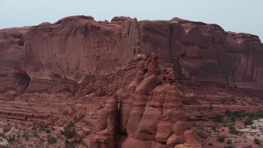 A majestic aerial view slowly pulls away from towering red rock spires and fins in a vast desert canyon landscape