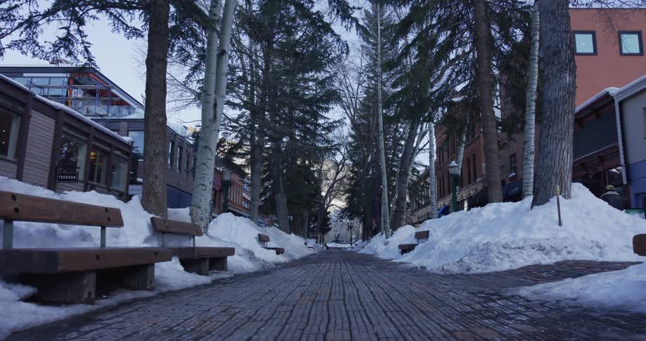 A low-angle shot of a quiet, snow-covered pedestrian street in a mountain resort town during winter