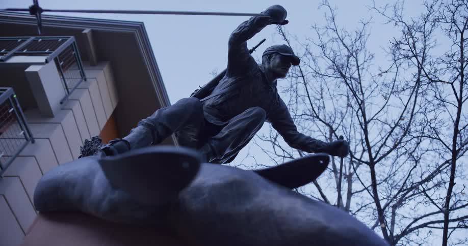 A low-angle static shot of the 10th Mountain Division Memorial statue in Vail, Colorado, depicting a skiing soldier against a cool sky