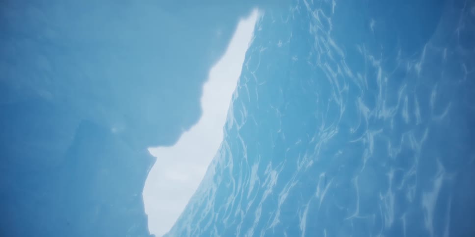 An ethereal low-angle shot from inside a brilliant blue ice cave reveals a sliver of bright sky