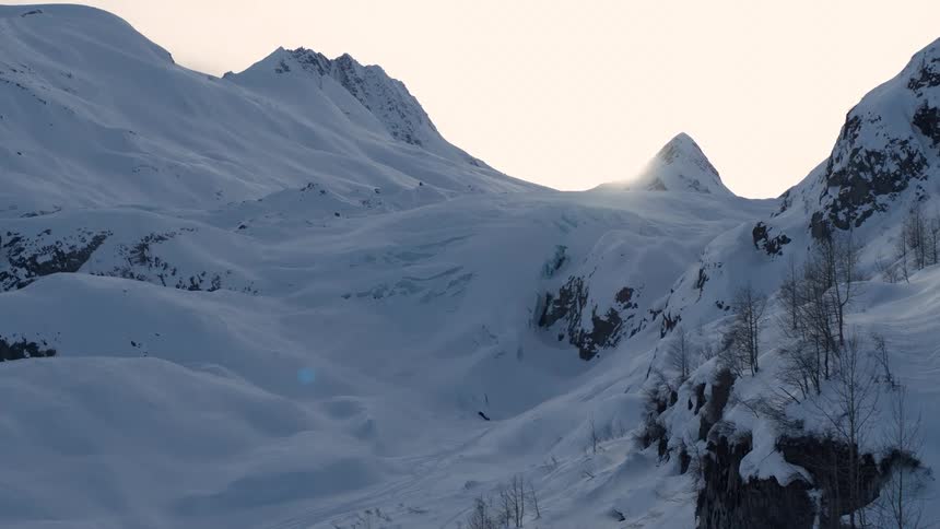 Expansive aerial view of a glacier-carved valley covered in fresh snow at dawn