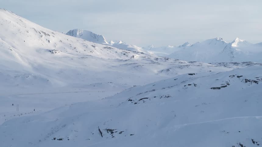 A scenic train journey reveals the majestic, snow-covered mountains of the Nordland Line in Norway