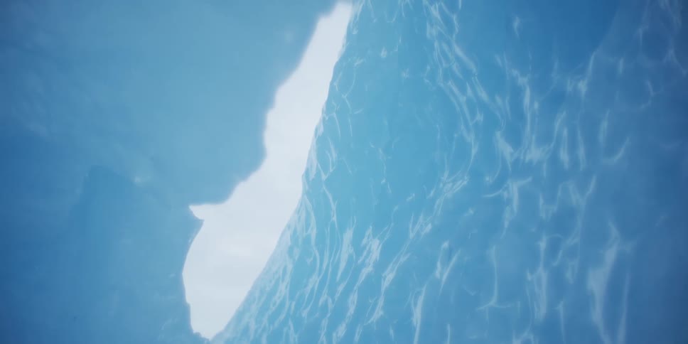 An abstract cinemagraph shows shimmering light reflecting on the vibrant blue wall of an ice cave