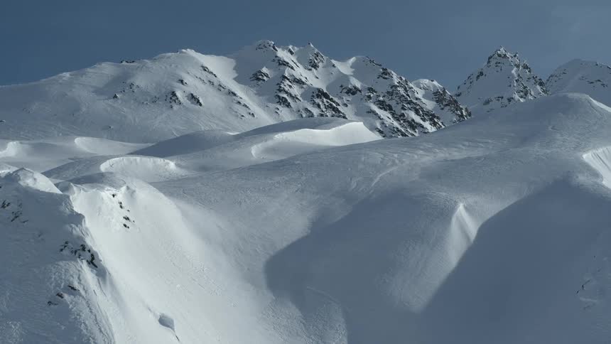A slow, breathtaking push-in shot captures the majestic and pristine beauty of a vast, snow-covered mountain range