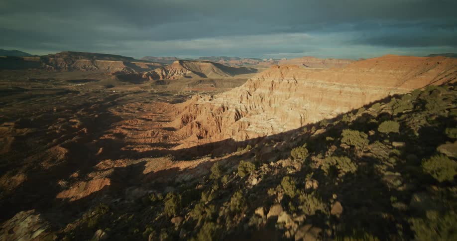 A cinematic FPV drone flight along a sun-kissed mountain ridge reveals a vast and breathtaking desert canyon landscape at sunrise