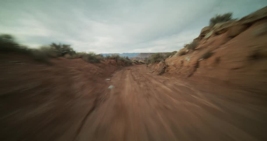 A thrilling first-person view of speeding along a rugged dirt trail in the arid desert landscape